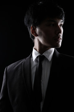 Asian man in black fomal suit in the dark