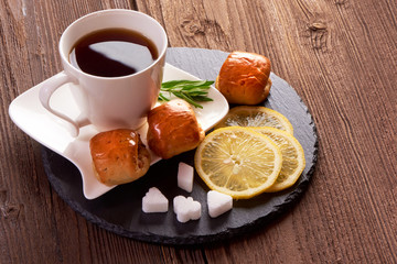 Buns with cup of tea on wooden background