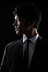 Asian man in black fomal suit in the dark
