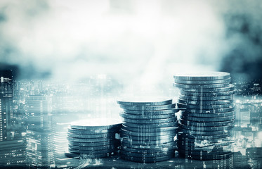 Double exposure of city and stack of coins for finance and banking concept