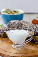 Cream sauce in a transparent glass bowl on wooden board.
