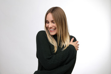 Hübsche blonde Frau mit langem Pullover lacht