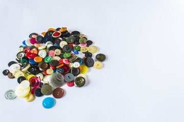 Many different buttons. Buttons for clothes made of plastic. Buttons are scattered on a light background. Many buttons.