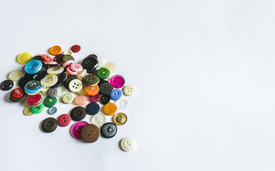 Many different buttons. Buttons for clothes made of plastic. Buttons are scattered on a light background. Many buttons.