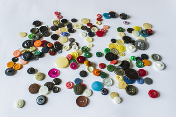 Many different buttons. Buttons for clothes made of plastic. Buttons are scattered on a light background. Many buttons.