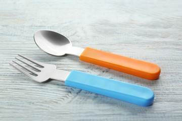 Colorful eating utensils for baby on wooden table