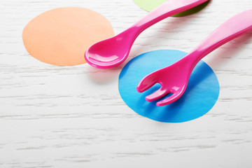 Colorful eating utensils for baby on wooden table