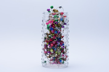 Unique jar with tiny colorful ornaments on white background
