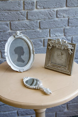 Old picture frames, lying mirror on the table with grey brick wall background remote view