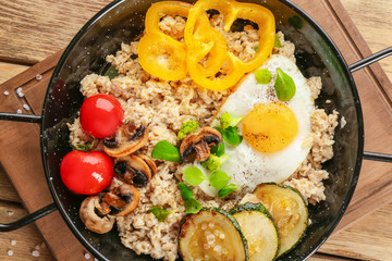 Frying egg with oatmeal, egg, mushrooms and vegetables on table