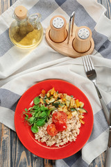 Plate with oatmeal and vegetables on table