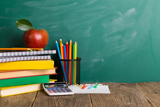 Back to school supplies. Books and blackboard on wooden background