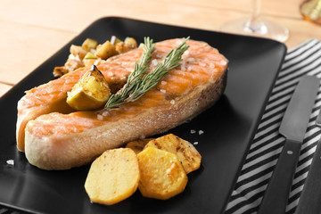 Plate with delicious salmon steak on table, closeup