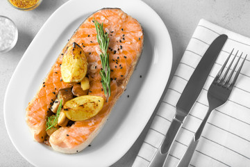Plate with delicious salmon steak on table