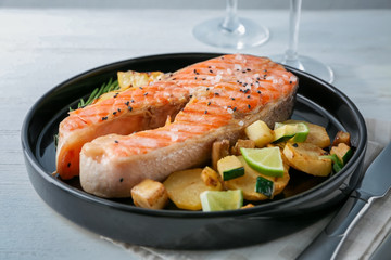 Plate with delicious salmon steak on table, closeup