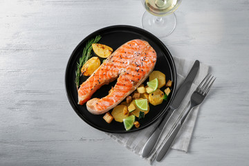 Plate with delicious salmon steak on table