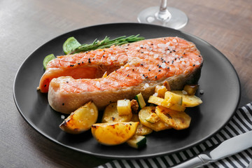 Plate with delicious salmon steak on table, closeup