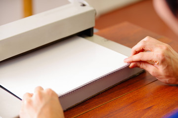Man organizing the documents using his hands to binding documents using a plastic ring binder machine, over a wooden table