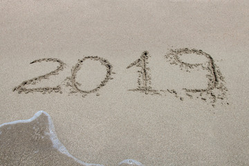 2019 written on the sand of a beach, closeup