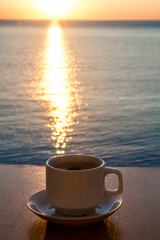 White Coffee cup in the morning time with sunrise path on the water.