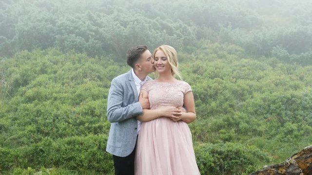 Luxury couple in evening dresses are hugging and kissing on the mountain meadow