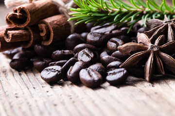 Coffee beans with cinnamon sticks, aniseeds, fir-tree branch on wooden background
