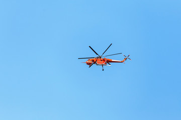 Naklejka na ściany i meble Red firefighter Helicopter flying fast in the blue sky during the emergency call in the city