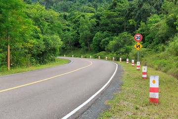 Traffic Signs and Bending Road to the Top of a Mountain with Green Trees