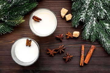 Celebrate new year winter evening with eggnog drink in glasses. Vanilla, spruce branch and cinnamon . Wooden desk background top view