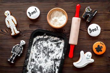 Cook halloween gingerbread cookies in shape of skeleton, mummy. Sweets near desk and rolling pin....