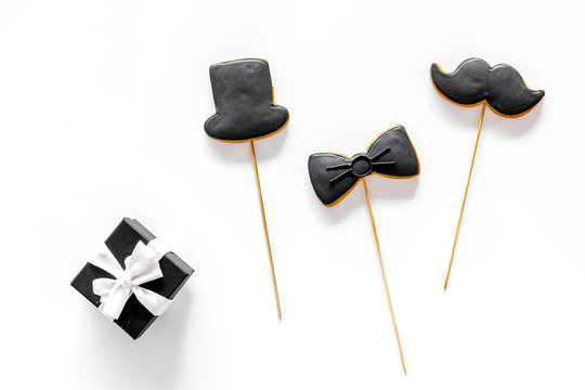 Father's day or birthday celebration with present, black tie, mustache and hat sign cookies on white background flat lay