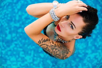 Portrait of a young sexy woman looking upwards in a swimming pool with wet hair