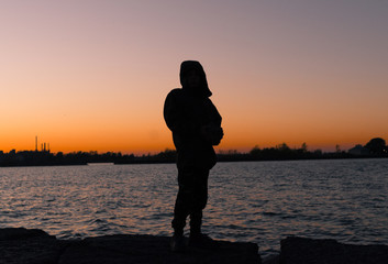 Silhouette of a Young Man on the Coastline at Sunset