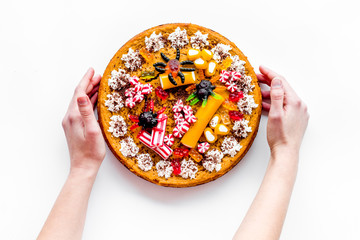 Hand take pumpkin pie for halloween decorated gummy spiders. White background top view