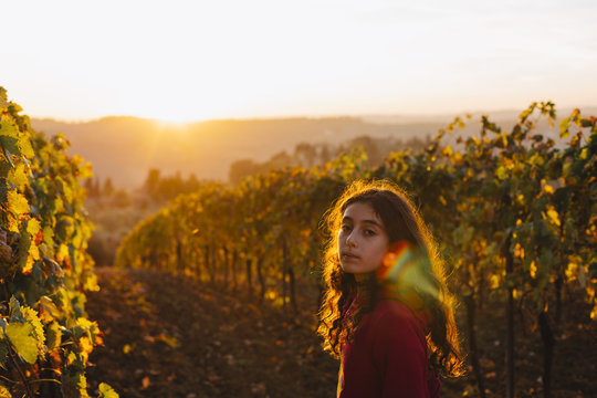 Girl turning back looking at camera in a vineyard