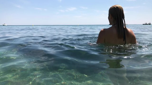 Female plays in crystal clear sea water slow-mo footage - Caucasian woman on French coast slow motion