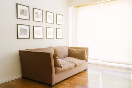 Sofa with pictures in a room with wooden floor and sunset sunlight