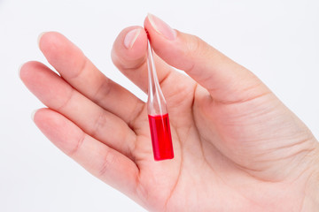 doctor hand holds glass ampoule with red medicine liquid3