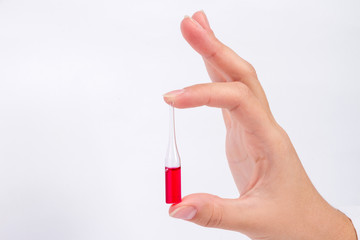 doctor hand holds glass ampoule with red medicine liquid