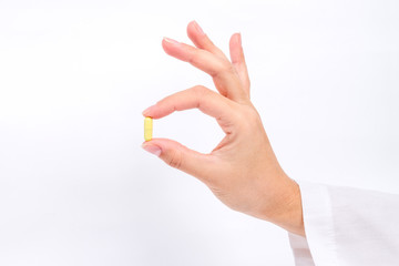 doctor's hand holds the yellow capsule