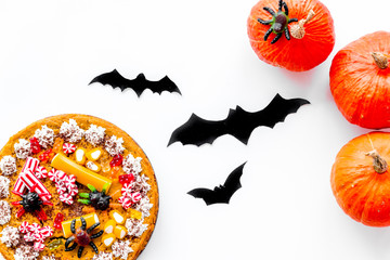 Pie for halloween with gummy spiders near pumpkins and paper bats on white background top view