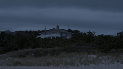 Exterior luxury beach front summer home during evening night time. Wide establishing photo generic location for hamptons or California coast house sit high on sand dune