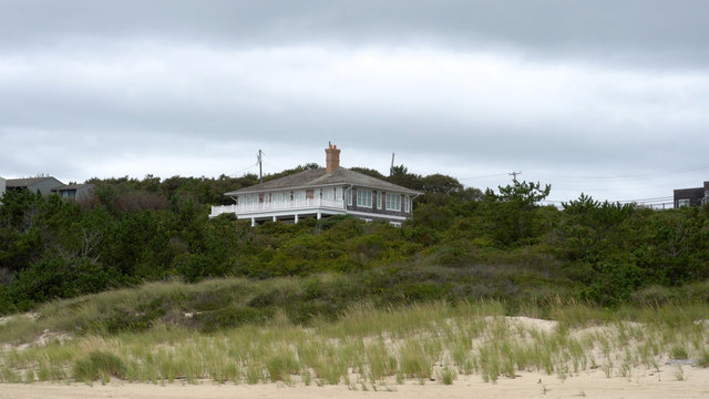 Exterior luxury beach front summer home during day time. Wide establishing photo generic location for hamptons or California coast house sit high on sand dune
