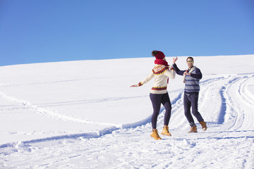 Carefree happy young couple having fun together in snow.