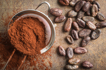 Dark cocoa powder in a sieve and cocoa beans.