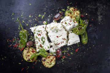 Traditional Greek feta with vegetable peperoni as top view with copy space on an old rustic board