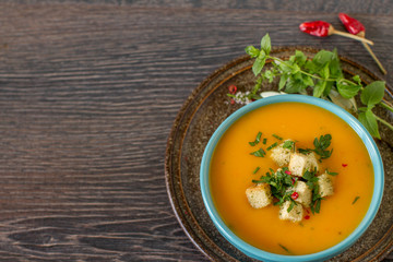 Pumpkin soup with cream and parsley on dark wooden background