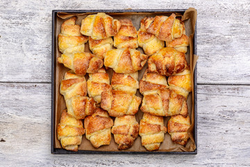 handmade croissants on a backing tray on a wooden background