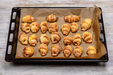 handmade croissants on a backing tray on a wooden background