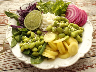 Vegetarian buddha bowl. Cooked rice, beans, edamame , striped beets, red cabbage, yellow carrots.